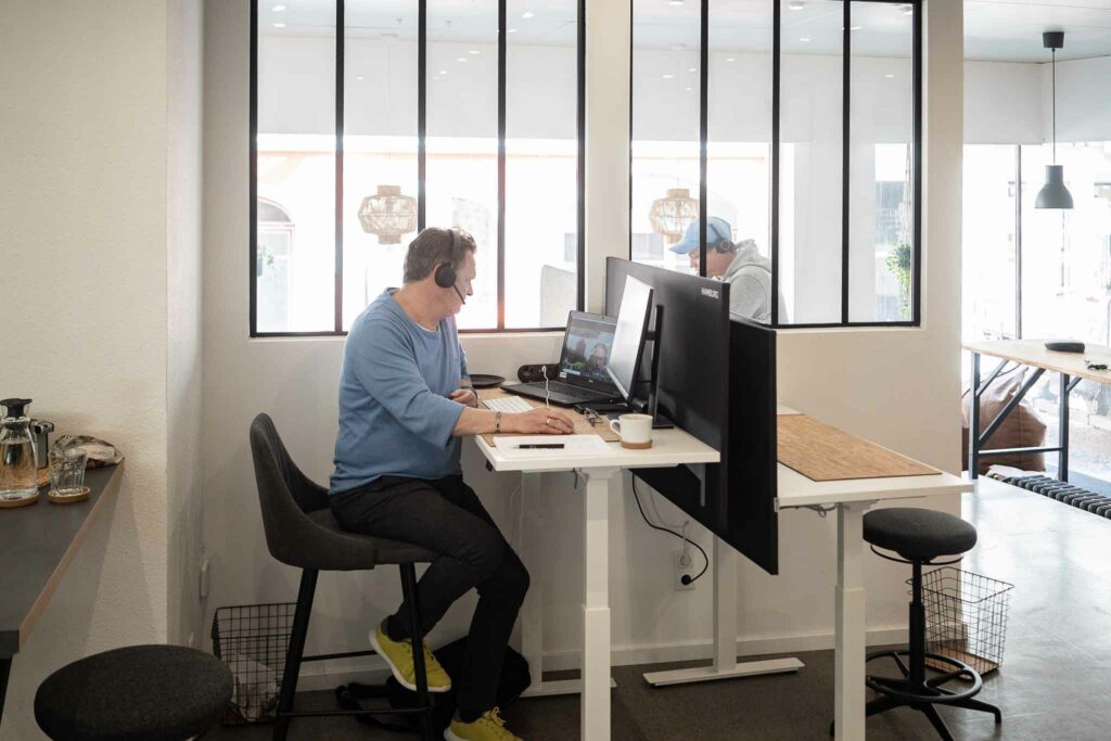 Coworker am Arbeitsplatz mit PC und Kopfhörern